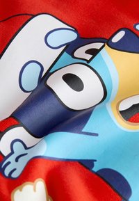 Roter Stoff mit einem Cartoon-Charakterdesign, das blaue, schwarze und gelbe Akzente aufweist. Glatte Textur mit sichtbaren Druckdetails.