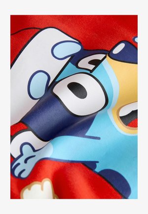 Tesătură roșie cu un design de personaj de desen animat, având accente albastre, negre și galbene. Textură netedă cu detalii de print vizibile.