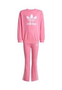 Ružová mikina a zodpovedajúce zvonové nohavice, vyrobené z mäkkej tkaniny, s bielym logom a pruhmi Adidas. Neformálne, pohodlné športové oblečenie.