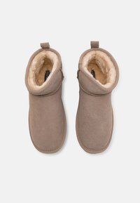 Brązowe botki za kostkę wykonane z miękkiego zamszu, z podszyciem z futerka ekologicznego, posiadające odwijany wierzch oraz pętlę z tyłu ułatwiającą zakładanie.