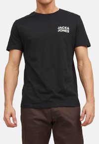 Black cotton t-shirt with short sleeves, featuring a white logo "JACK & JONES" on the left chest. Classic crew neck design.