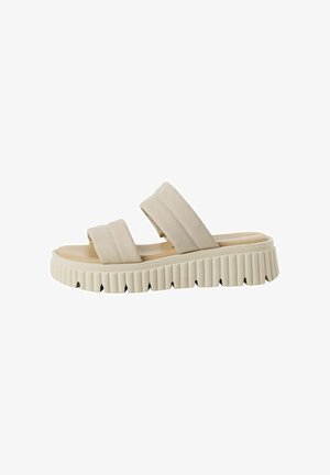 Beige slidesandal med två breda remmar, formad fotbädd och tjock räfflad sula. Materialet ser mjukt ut och har en slät yta.