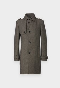 Brun herringbone-kappa med krage, fyra knappar och justerbara ärmslut. Har en axelrem och en slät textur.