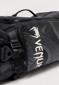 Must seljakott tekstuurse mustriga ja Venum logo valgena. Varustatud lukustatava sulgemise ja reguleeritavate rihmadega mugavuse tagamiseks.