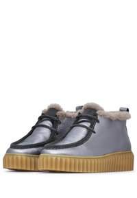 Bottines en cuir argenté avec une doublure en fourrure beige, des accents noirs et une semelle en caoutchouc striée. Dotées d'un système de laçage à l'avant.