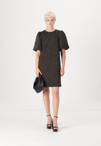 Vestido de manga curta, texturizado em tons escuros, com uma silhueta descontraída. Complementa com uma bolsa preta e sandálias de plataforma.