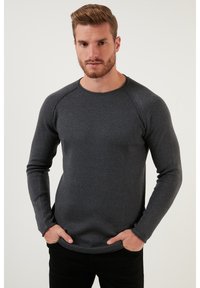 Cămașă din material texturat, de culoare gri închis, cu mânecă lungă, cu revere și manșete raglan, cu gât rotund, se potrivește strâns în jurul trunchiului.