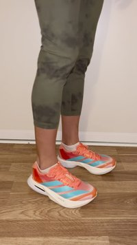 Running shoes featuring a gradient design in orange and red, with blue stripes. Made of mesh and synthetic materials, with a white sole.