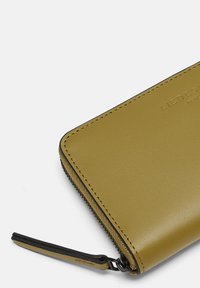 Portefeuille en cuir vert avec une texture lisse, doté d'une fermeture éclair et d'une languette attachée. Marque en relief à la surface.