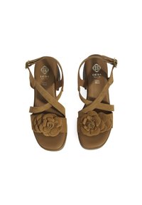 Brown suede sandals with a floral design on the straps, featuring crisscross ankle straps and a cushioned sole for comfort.