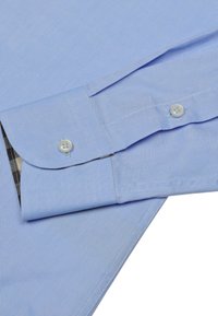 Helles blaues Hemd aus Stoff mit kariertem Innenmanschette. Verfügt über geknöpfte Manschetten, glatte Textur und einen klaren Kragen.