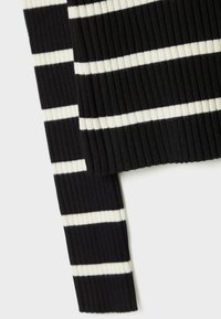 Pull à côtes avec des rayures horizontales noir et blanc. La texture est marquée, avec des couleurs contrastantes mettant en valeur le design.