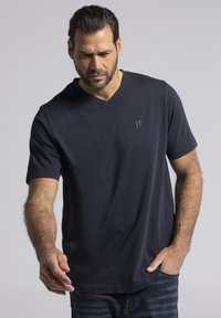 Camiseta de cuello en V azul marino hecha de una tela suave, con mangas cortas y un sutil logo en el pecho, combinada con jeans de mezclilla.