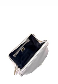 Borsa a mano bianca in pelle con chiusura a cerniera, caratterizzata da una fodera in tessuto scuro e una tasca interna con un piccolo accento dorato.