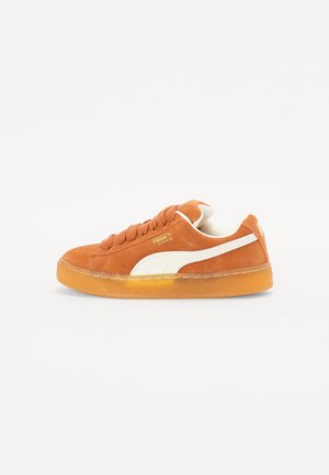 Orange ruskind sneakers med hvide accenter, der har en rund tå, flade snørebånd og en struktureret gummisål. Guld logo på siden.