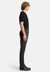 Schwarzes Kurzarm-T-Shirt, dunkelbraune Slim-Fit-Jeans und schwarze Knöchelstiefel; seitliche Ansicht, die Passform und Proportionen zeigt.