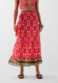 Gonna maxi a fiori in rosa, con orlo arricciato e dettagli verdi. Realizzata in tessuto leggero con un nastro legato.