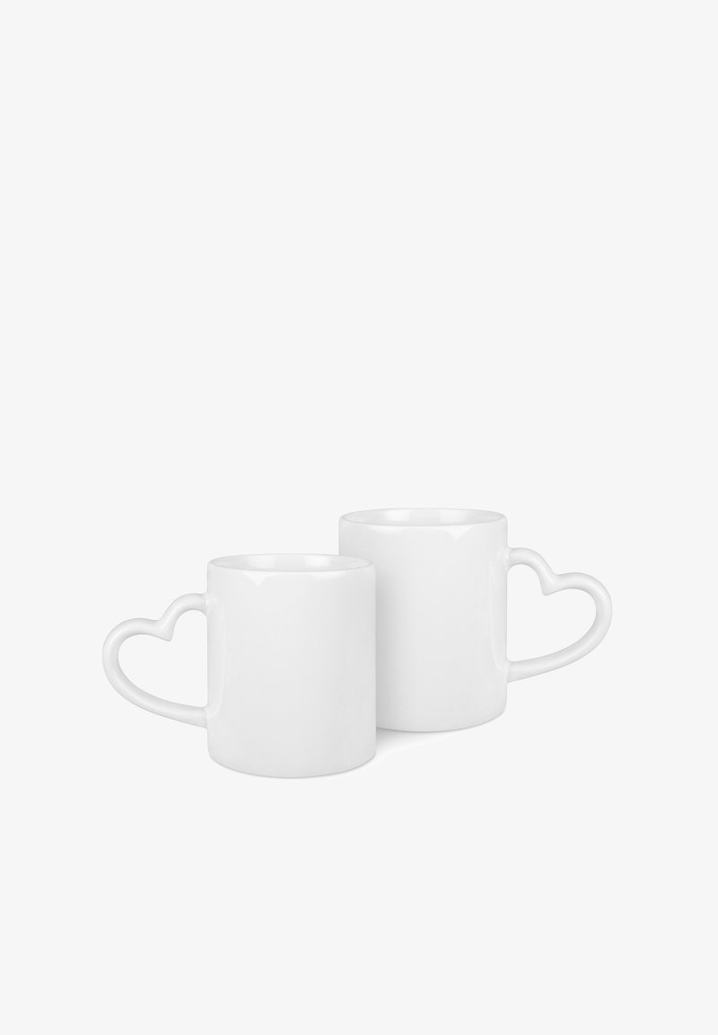 Białe ceramiczne kubki z uchwytami w kształcie serca, cylindryczny kształt, błyszczące wykończenie, z jednym wyższym i jednym niższym kubkiem.