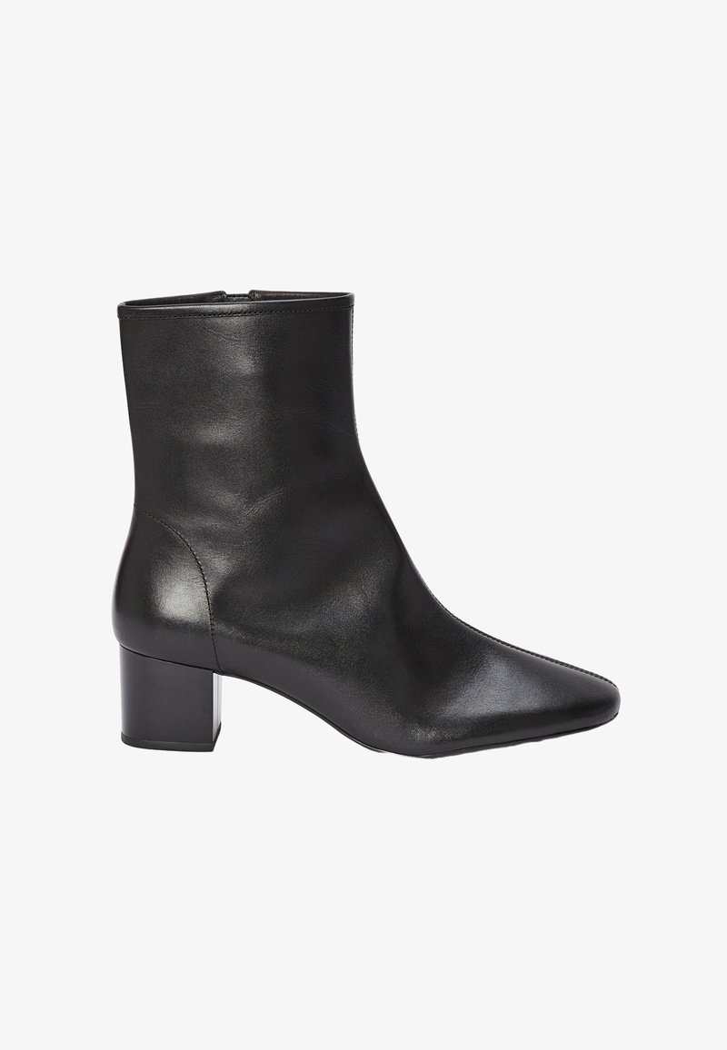 Bottine en cuir noir avec un bout pointu, une texture lisse et un talon bloc pour la stabilité. Présente un design élégant et minimaliste.