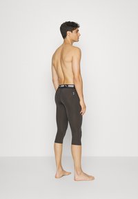 Fekete sportcapri leggings, testhezálló kialakítással, rugalmas anyaggal és márkás derékrésszel. A térd alatt végződik.