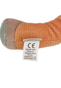 Plush toy in orange and tan corduroy with a smooth grey fabric tip. Includes a care label with manufacturer details. Soft texture.