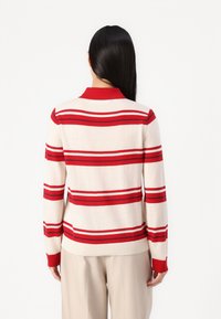 Red and cream striped sweater with a ribbed collar and cuffs, crafted from soft knit material, featuring long sleeves and a fitted waist.