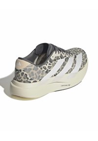 Graue und beige Sneaker mit einem Obermaterial im Leopardenmuster, transparenten Akzenten und drei weißen Streifen. Hat eine dicke, hellfarbige Sohle.