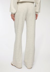 Jasnoszare spodnie dzwony z miękkiego materiału, o gładkiej fakturze i wysokim stanem. Minimalistyczne detale i elegancka sylwetka.