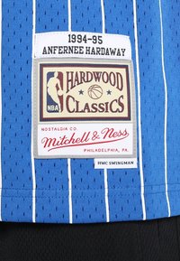 Maillot de basket-ball bleu avec des rayures blanches verticales, une étiquette « Hardwood Classics » et un logo « Mitchell & Ness » en bas.