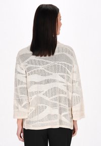 Beige gestrickter Pullover mit einem strukturierten, geometrischen Muster und Dreiviertelärmeln. Die lockere Passform erhöht den Tragekomfort und die Atmungsaktivität.