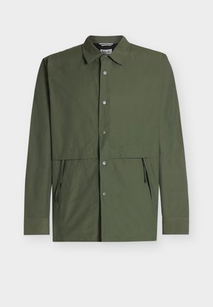 Giacca verde oliva a maniche lunghe con chiusura frontale a bottoni, tasche laterali con zip e colletto classico, mostrata su sfondo bianco.