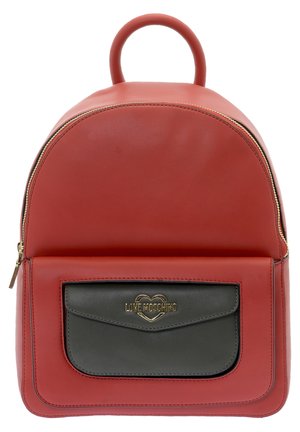 Sac à dos en cuir rouge avec une forme arrondie, doté d'une poche grise à l'avant. Les accessoires en métal doré comprennent un logo de la marque sur la poche.