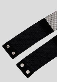 Fascia elastica nera con tessuto testurizzato, dettagli in nero liscio e bottoni a pressione argentati. Strass decorativi su un lato.