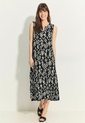 Abito maxi senza maniche di colore nero con intricate fantasie bianche, forma A-line, scollo rotondo e design a strati della gonna.