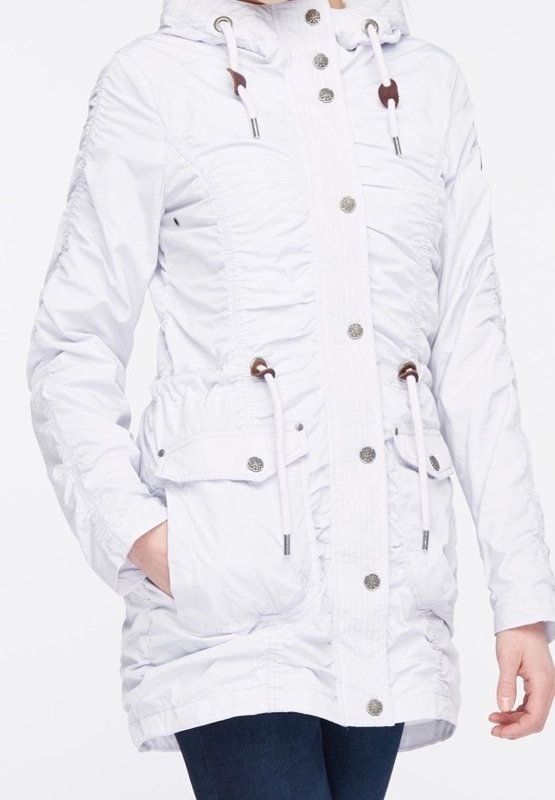 Veste isolante blanche avec une texture froncée, capuche à cordon de serrage, poches avant, garnie de ferrures argentées et fermeture à boutons.