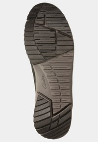 Black rubber shoe sole with textured tread pattern. Features reinforced edges and side grooves for enhanced grip and stability.
