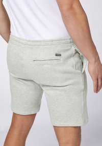 Gray cotton blend shorts with an elastic waistband, side pockets, and a single back pocket featuring a label. Simple, fitted design.