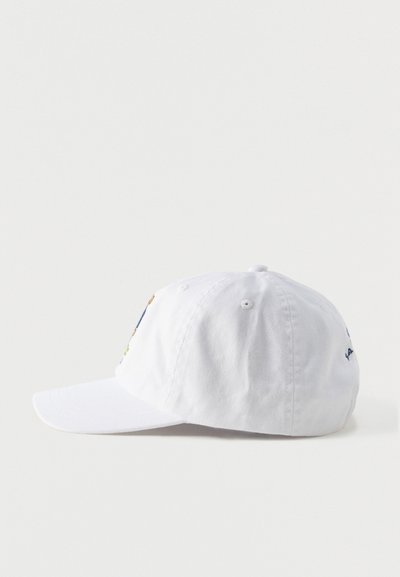 Λευκό βαμβακερό καπέλο μπέιζμπολ με καμπυλωτό γείσο, οπές αερισμού και μικρό κεντημένο λογότυπο στο πλάι, εμφανίζεται από την αριστερή πλευρά.