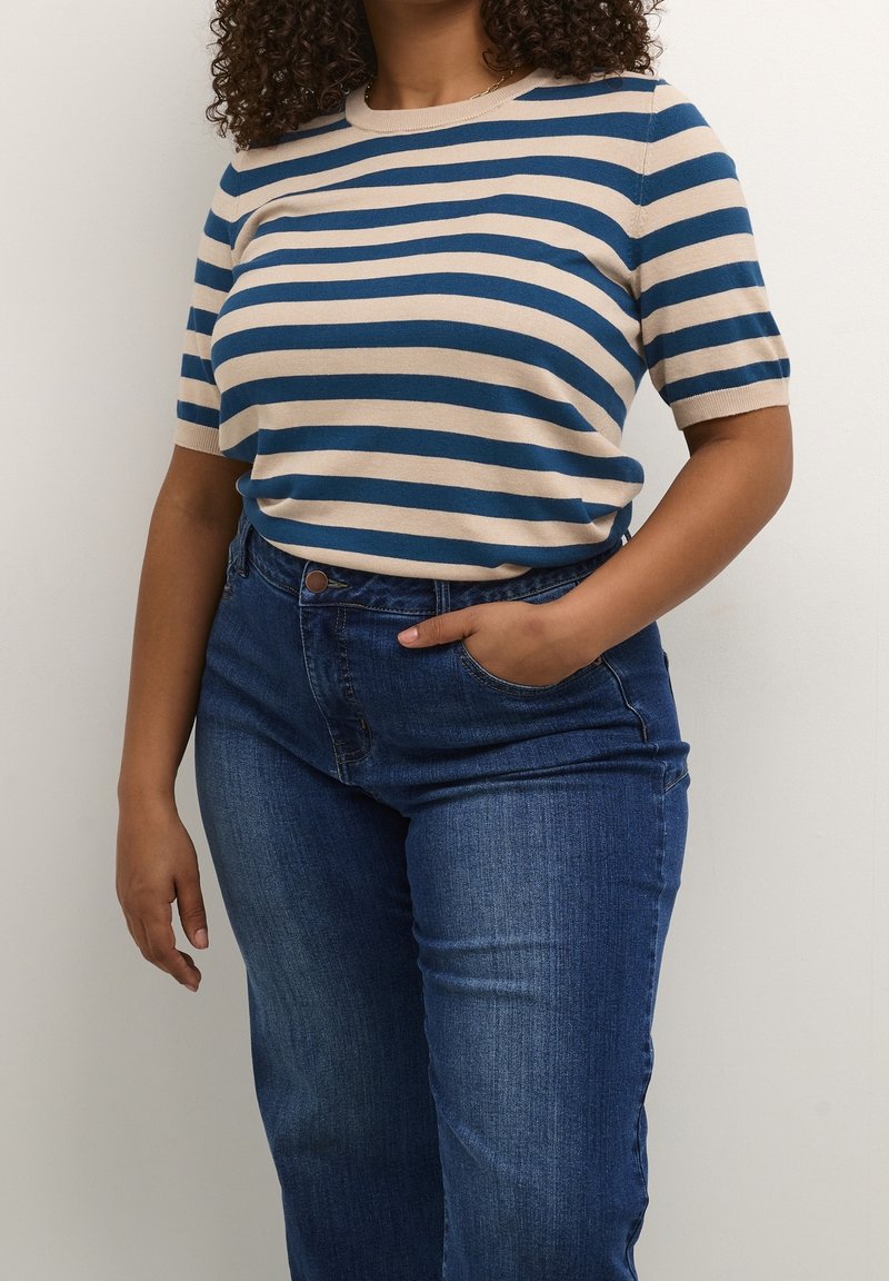 Stribet strikket kortærmet sweater i beige og blå, parret med højtaljede mørk vaskede jeans. Blød tekstur, afslappet pasform og rund halsudskæring.