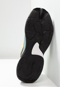 Semelle de sneaker en caoutchouc noir présentant des motifs de sculpture texturée; dotée d'accents turquoise et blancs, et d'une forme courbée et aérodynamique.