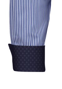 Manica di camicia a righe blu e bianche con polsino blu scuro caratterizzato da un motivo a rombi. Texture liscia, vestibilità sartoriale.