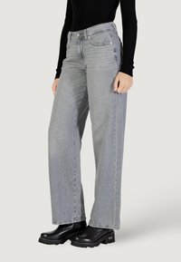 Jeans grigi larghi in denim con una finitura sbiadita, dotati di vita alta, tasche frontali e dettagli di cucitura a contrasto.