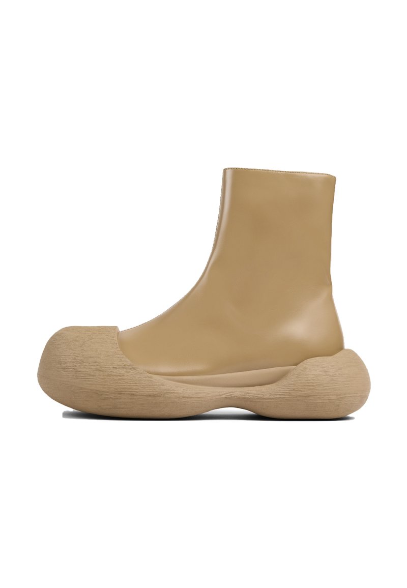 Tan gummistövlar vid ankeln med en rundad träliknande sula och slät yta, som har en strömlinjeformad design och minimalistisk silhuett.