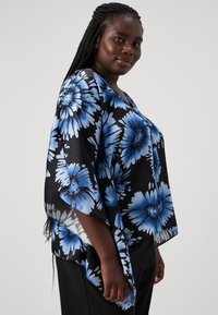 Svarte blomstermønstrede kimono-topper med blå blomster og svarte detaljer, flytende design, lett stoff, V-hals og avslappet passform.