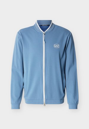 Light blue zip-up jacket with white trim, ribbed cuffs, and a small EA7 Emporio Armani logo on the left chest.