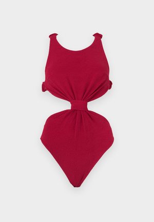 Κόκκινο ολόσωμο μαγιό με υφή υφάσματος, φαρδιές τιράντες, κεντρικό άνοιγμα και λεπτομέρεια ζώνης στη μέση.