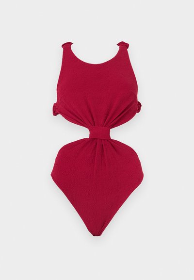 Κόκκινο ολόσωμο μαγιό με υφή υφάσματος, φαρδιές τιράντες, κεντρικό άνοιγμα και λεπτομέρεια ζώνης στη μέση.