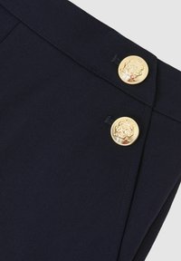 Pantaloni din stofă bleumarin cu nasturi aurii distinctivi, cu un design în relief. Textură netedă, linii clare și croială ajustată.