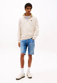 Kermaansininen poolopaita, yhdistetty sinisiin farkkushortseihin. Asun täydentävät valkoiset lenkkarit ja nilkkapituiset sukat.