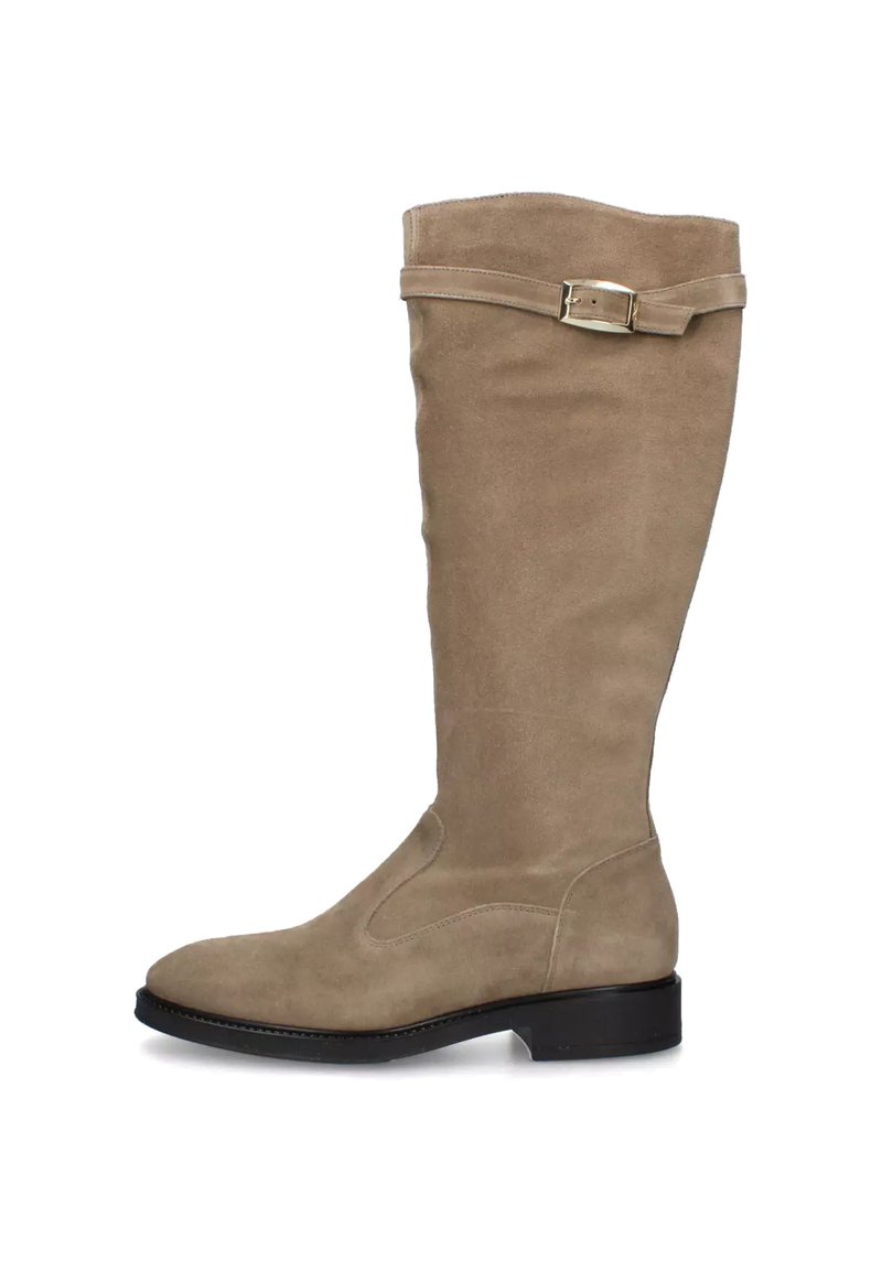 Bota alta de gamuza beige con un tacón negro bajo y una correa decorativa con hebilla dorada cerca de la parte superior.